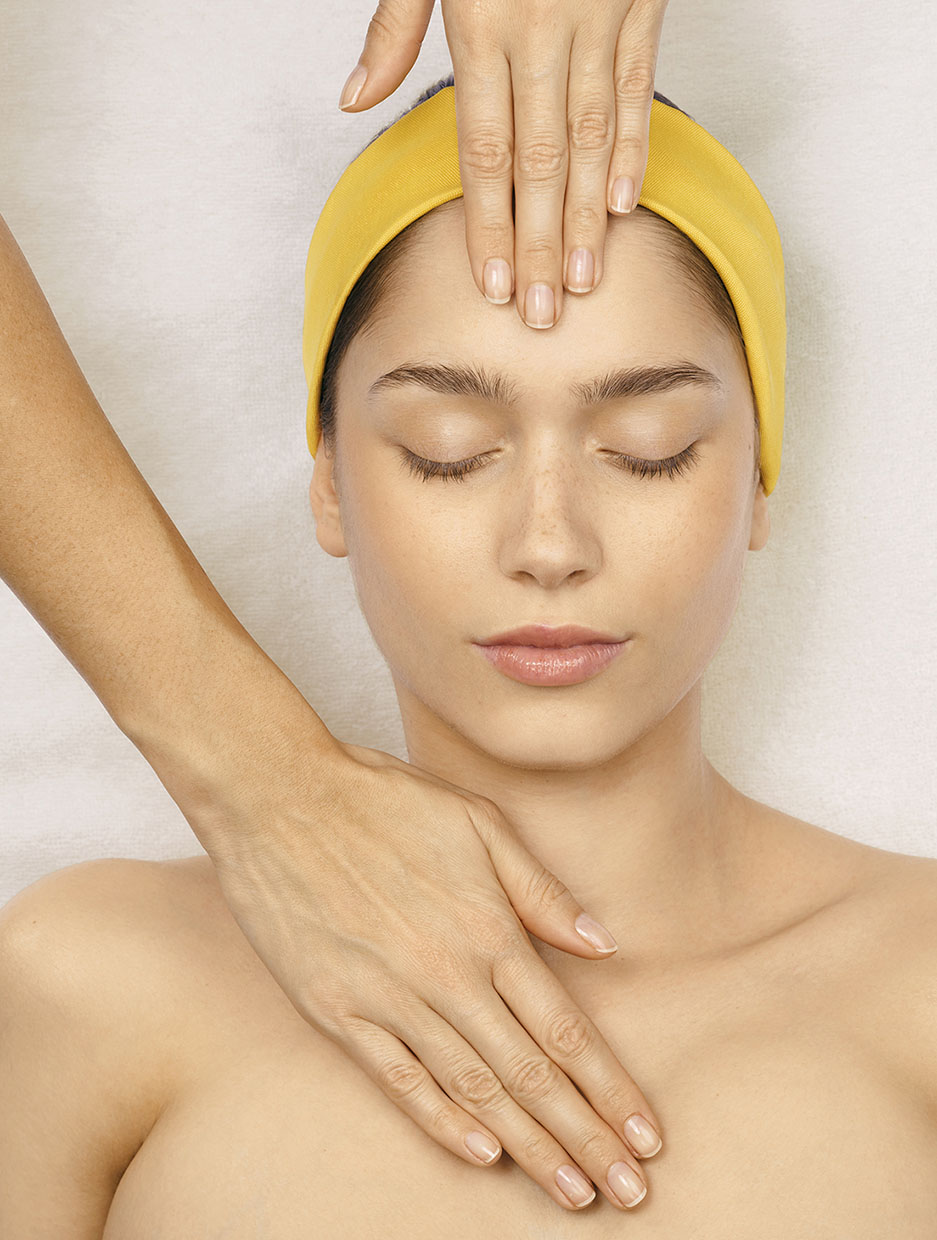 portrait d'une femme avec les mains d'une masseuse posées sur son front et son sternum