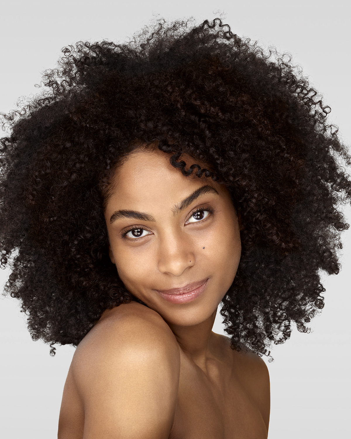 jeune femme à la coupe afro de face avec l'épaule dénudée