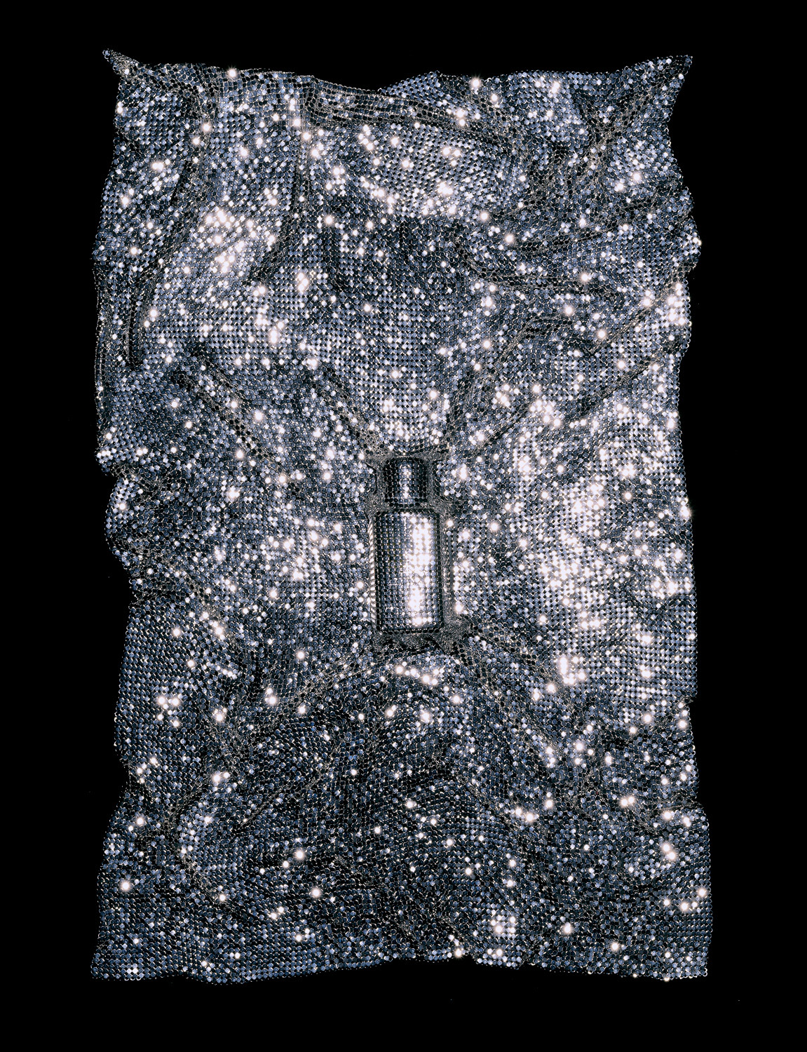 Parfum Les Exclusifs de Chanel caché sous un tissu métallique